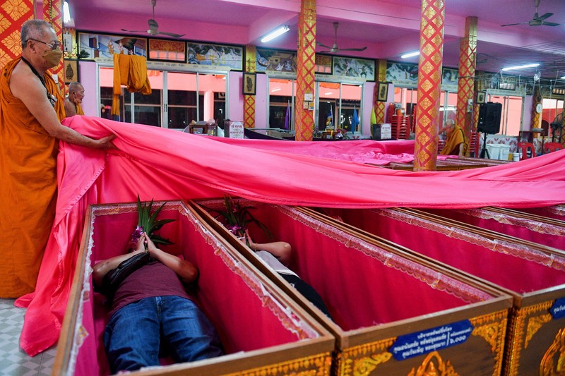 Umat berbaring dan berdoa di dalam peti mati untuk menghilangkan nasib buruk dan terlahir kembali untuk awal yang baru di Tahun Baru di sebuah kuil di Nonthaburi, di pinggiran Bangkok, Thailand 2 Januari 2023. (REUTERS/Chalinee Thirasupa)