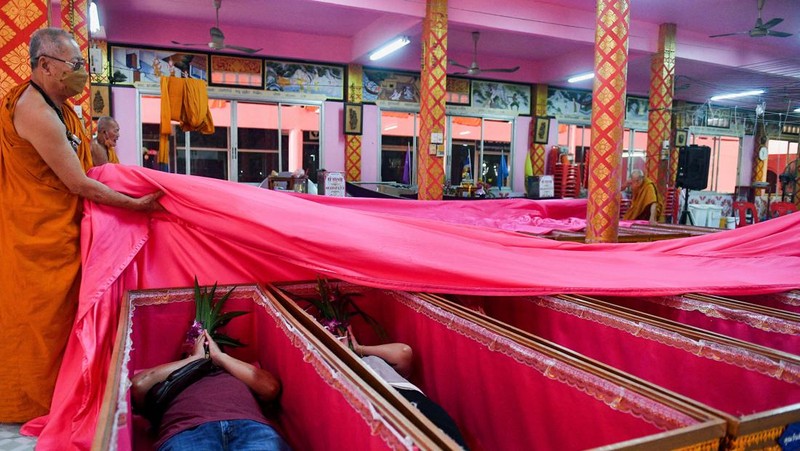 Umat berbaring dan berdoa di dalam peti mati untuk menghilangkan nasib buruk dan terlahir kembali untuk awal yang baru di Tahun Baru di sebuah kuil di Nonthaburi, di pinggiran Bangkok, Thailand 2 Januari 2023. (REUTERS/Chalinee Thirasupa)