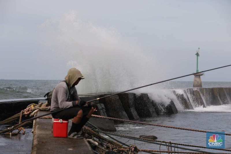 Warga memancing saat ombak besar di kawasan pelabuhan Muara Baru, Jakarta, Senin (2/1/2023). Warga memancing saat ombak besar di kawasan pelabuhan Muara Baru, Jakarta, Senin (2/1/2023). Pemerintah pusat bersama Pemerintah Provinsi DKI Jakarta tengah melakukan pembangunan tanggul pantai di wilayah utara Jakarta. (CNBC Indonesia / Tri Susilo)