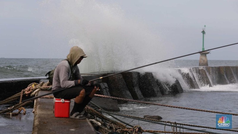 Warga memancing saat ombak besar di kawasan pelabuhan Muara Baru, Jakarta, Senin (2/1/2023). Pemerintah pusat bersama Pemerintah Provinsi DKI Jakarta tengah melakukan pembangunan tanggul pantai di wilayah utara Jakarta. (CNBC Indonesia / Tri Susilo)