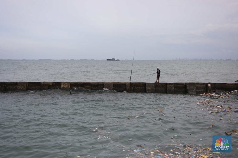 Warga memancing saat ombak besar di kawasan pelabuhan Muara Baru, Jakarta, Senin (2/1/2023). Warga memancing saat ombak besar di kawasan pelabuhan Muara Baru, Jakarta, Senin (2/1/2023). Pemerintah pusat bersama Pemerintah Provinsi DKI Jakarta tengah melakukan pembangunan tanggul pantai di wilayah utara Jakarta. (CNBC Indonesia / Tri Susilo)
