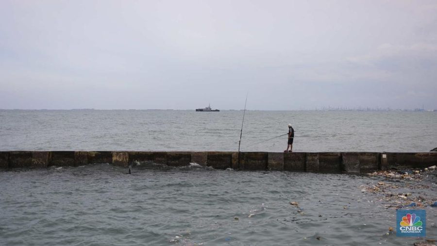 Warga memancing saat ombak besar di kawasan pelabuhan Muara Baru, Jakarta, Senin (2/1/2023). Pemerintah pusat bersama Pemerintah Provinsi DKI Jakarta tengah melakukan pembangunan tanggul pantai di wilayah utara Jakarta. (CNBC Indonesia / Tri Susilo)