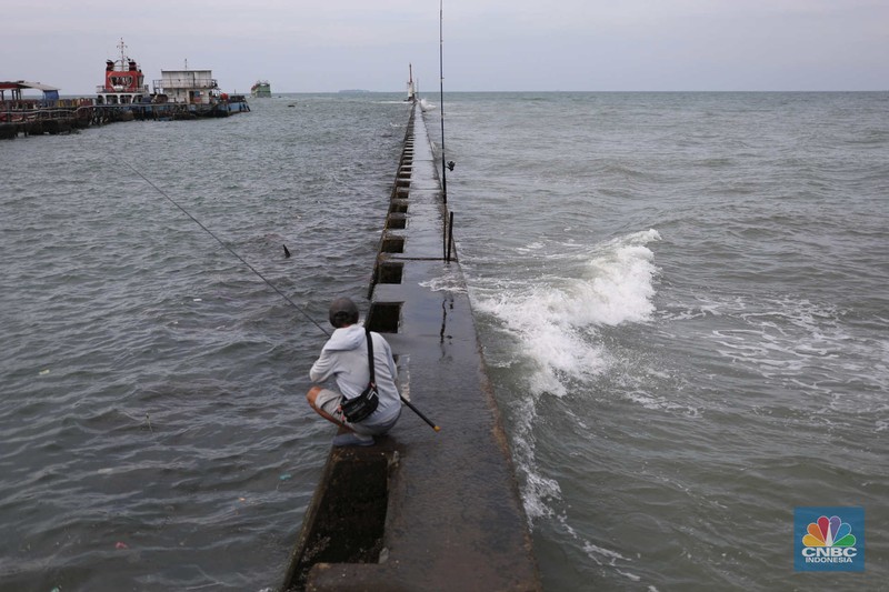 Warga memancing saat ombak besar di kawasan pelabuhan Muara Baru, Jakarta, Senin (2/1/2023). Warga memancing saat ombak besar di kawasan pelabuhan Muara Baru, Jakarta, Senin (2/1/2023). Pemerintah pusat bersama Pemerintah Provinsi DKI Jakarta tengah melakukan pembangunan tanggul pantai di wilayah utara Jakarta. (CNBC Indonesia / Tri Susilo)