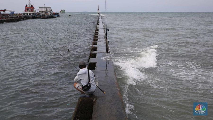 Warga memancing saat ombak besar di kawasan pelabuhan Muara Baru, Jakarta, Senin (2/1/2023). Pemerintah pusat bersama Pemerintah Provinsi DKI Jakarta tengah melakukan pembangunan tanggul pantai di wilayah utara Jakarta. (CNBC Indonesia / Tri Susilo)