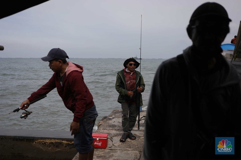Warga memancing saat ombak besar di kawasan pelabuhan Muara Baru, Jakarta, Senin (2/1/2023). Warga memancing saat ombak besar di kawasan pelabuhan Muara Baru, Jakarta, Senin (2/1/2023). Pemerintah pusat bersama Pemerintah Provinsi DKI Jakarta tengah melakukan pembangunan tanggul pantai di wilayah utara Jakarta. (CNBC Indonesia / Tri Susilo)