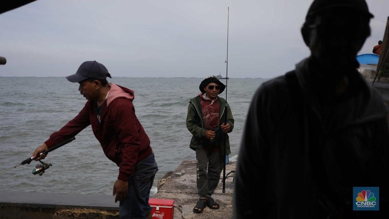 Warga memancing saat ombak besar di kawasan pelabuhan Muara Baru, Jakarta, Senin (2/1/2023). Pemerintah pusat bersama Pemerintah Provinsi DKI Jakarta tengah melakukan pembangunan tanggul pantai di wilayah utara Jakarta. (CNBC Indonesia / Tri Susilo)