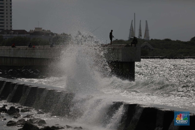 Warga memancing saat ombak besar di kawasan pelabuhan Muara Baru, Jakarta, Senin (2/1/2023). Warga memancing saat ombak besar di kawasan pelabuhan Muara Baru, Jakarta, Senin (2/1/2023). Pemerintah pusat bersama Pemerintah Provinsi DKI Jakarta tengah melakukan pembangunan tanggul pantai di wilayah utara Jakarta. (CNBC Indonesia / Tri Susilo)
