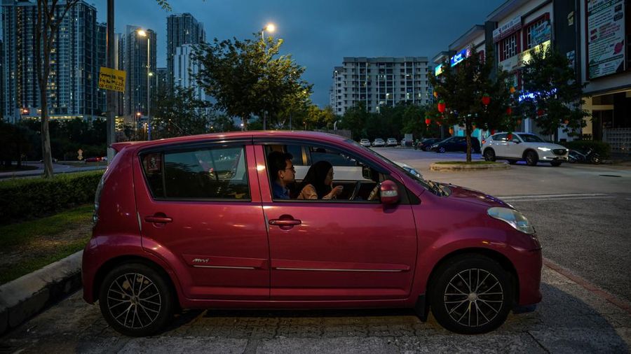 This picture taken on February 9, 2021 shows a couple eating dinner in their car outside the Padi House restaurant in Cyberjaya, outside Kuala Lumpur. - Lockdown-weary Malaysians have jumped at the chance for an unusual eating-out experience allowing them to enjoy restaurant food despite coronavirus curbs -- in-car dining. (Photo by Mohd RASFAN / AFP) (Photo by MOHD RASFAN/AFP via Getty Images)
