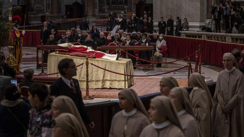 Orang-orang mengantre untuk memasuki Basilika Santo Petrus tempat mendiang Paus Benediktus XVI disemayamkan di Vatikan, Senin (2/1/2023). Ribuan orang memberi penghormatan terakhir untuk Paus Benediktus, teolog Jerman yang akan dikenang sebagai paus pertama dalam 600 tahun yang mengundurkan diri sejak Gregory XII tahun 1415 silam. Ia meninggal pada Sabtu (31/12) waktu setempat dalami usia 95 tahun dan pemakamannya akan diadakan Kamis, 5 Januari 2023. (AP Photo/Antonio Calanni)