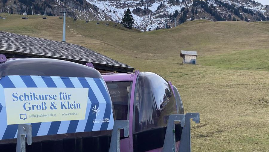Skiers speed down a ski slope with artificial snow in the middle of a snowless field, at 1600 meters above sea level, in the alpine resort of Villars-sur-Ollon, Switzerland, Saturday, Dec. 31, 2022. Sparse snowfall and unseasonably warm weather in much of Europe is allowing green grass to blanket many mountaintops across the region where snow might normally be. It has caused headaches for ski slope operators and aficionados of Alpine white this time of year. (Laurent Gillieron/Keystone via AP)