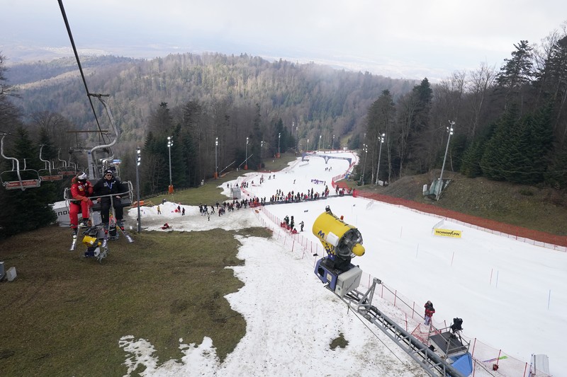 Europe Alps Snow Shortage Skiers speed down a ski slope with artificial snow in the middle of a snowless field, at 1600 meters above sea level, in the alpine resort of Villars-sur-Ollon, Switzerland, Saturday, Dec. 31, 2022. Sparse snowfall and unseasonably warm weather in much of Europe is allowing green grass to blanket many mountaintops across the region where snow might normally be. It has caused headaches for ski slope operators and aficionados of Alpine white this time of year. (Laurent Gillieron/Keystone via AP)
