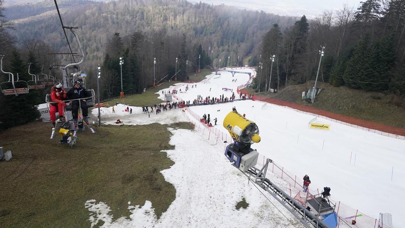 Skiers speed down a ski slope with artificial snow in the middle of a snowless field, at 1600 meters above sea level, in the alpine resort of Villars-sur-Ollon, Switzerland, Saturday, Dec. 31, 2022. Sparse snowfall and unseasonably warm weather in much of Europe is allowing green grass to blanket many mountaintops across the region where snow might normally be. It has caused headaches for ski slope operators and aficionados of Alpine white this time of year. (Laurent Gillieron/Keystone via AP)