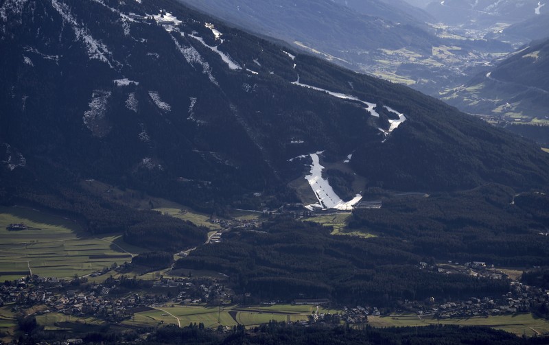 Skiers speed down a ski slope with artificial snow in the middle of a snowless field, at 1600 meters above sea level, in the alpine resort of Villars-sur-Ollon, Switzerland, Saturday, Dec. 31, 2022. Sparse snowfall and unseasonably warm weather in much of Europe is allowing green grass to blanket many mountaintops across the region where snow might normally be. It has caused headaches for ski slope operators and aficionados of Alpine white this time of year. (Laurent Gillieron/Keystone via AP)