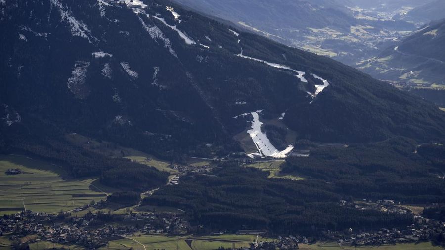 Skiers speed down a ski slope with artificial snow in the middle of a snowless field, at 1600 meters above sea level, in the alpine resort of Villars-sur-Ollon, Switzerland, Saturday, Dec. 31, 2022. Sparse snowfall and unseasonably warm weather in much of Europe is allowing green grass to blanket many mountaintops across the region where snow might normally be. It has caused headaches for ski slope operators and aficionados of Alpine white this time of year. (Laurent Gillieron/Keystone via AP)