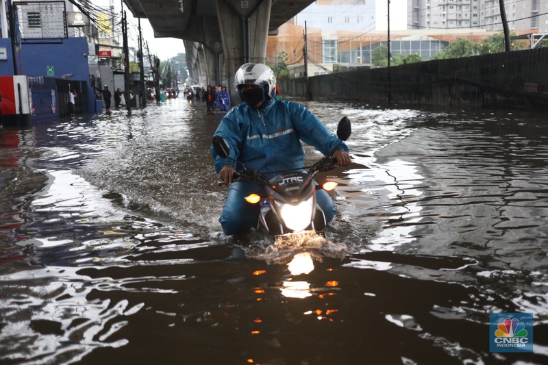 Warga menerobos banjir menggunakan sepeda motor di kawasan Seskol, Jakarta, Rabu (4/1/2023). Hujan deras mengguyur sejumlah wilayah di DKI Jakarta. (CNBC Indonesia/Tri Susilo)