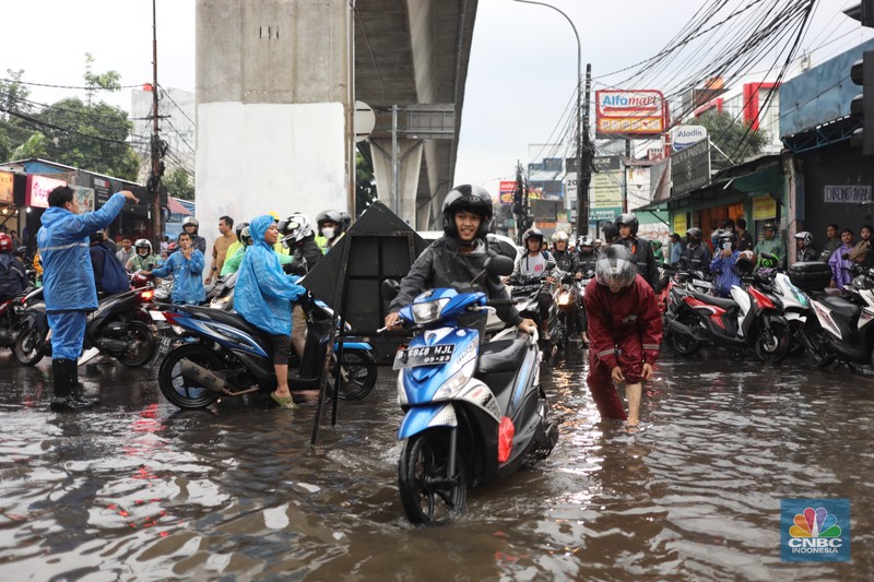Warga menerobos banjir menggunakan sepeda motor di kawasan Seskol, Jakarta, Rabu (4/1/2023). Hujan deras mengguyur sejumlah wilayah di DKI Jakarta. (CNBC Indonesia/Tri Susilo)