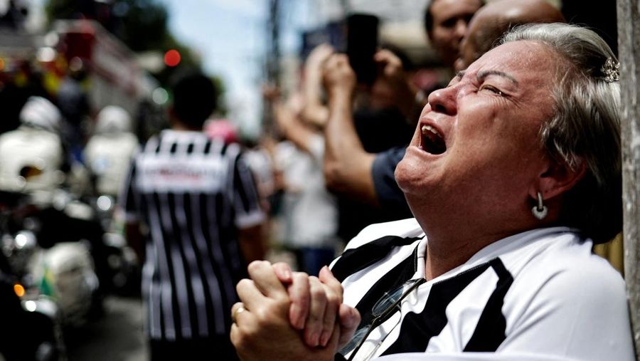 Sejumlah penggemar berkumpul saat mobil pemadam kebakaran yang membawa jenazah legenda sepak bola asal Brasil Pele melintas dari Stadion Vila Belmiro Santos untuk melakukan prosesi pemakaman di Santos, Brasil, Selasa (3/1/2022). Legenda sepak bola asal Brasil Pele meninggal dunia di usia 82 setelah berjuang melawan penyakit kanker usus besar, Kamis (29/12/2022) waktu setempat. (REUTERS/Amanda Perobelli)
