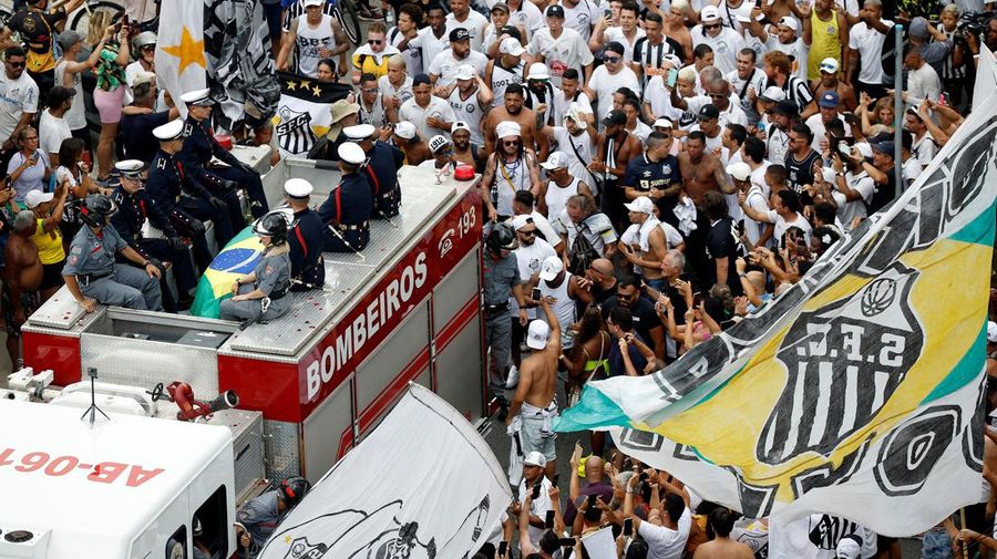 Sejumlah penggemar berkumpul saat mobil pemadam kebakaran yang membawa jenazah legenda sepak bola asal Brasil Pele melintas dari Stadion Vila Belmiro Santos untuk melakukan prosesi pemakaman di Santos, Brasil, Selasa (3/1/2022). Legenda sepak bola asal Brasil Pele meninggal dunia di usia 82 setelah berjuang melawan penyakit kanker usus besar, Kamis (29/12/2022) waktu setempat. (REUTERS/Amanda Perobelli)