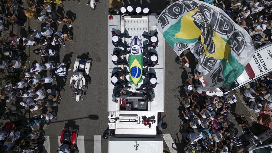 Sejumlah penggemar berkumpul saat mobil pemadam kebakaran yang membawa jenazah legenda sepak bola asal Brasil Pele melintas dari Stadion Vila Belmiro Santos untuk melakukan prosesi pemakaman di Santos, Brasil, Selasa (3/1/2022). Legenda sepak bola asal Brasil Pele meninggal dunia di usia 82 setelah berjuang melawan penyakit kanker usus besar, Kamis (29/12/2022) waktu setempat. (REUTERS/Amanda Perobelli)