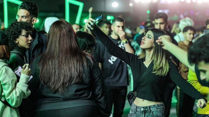 Perempuan Arab Saudi Menonton Konser Penonton menggunakan telepon untuk berswafoto selama festival musik MDLBEAST Soundstorm 2022 di Banban di pinggiran utara ibu kota Arab Saudi, Riyadh, Kamis (1/12/2022). (Photo by FAYEZ NURELDINE/AFP via Getty Images)