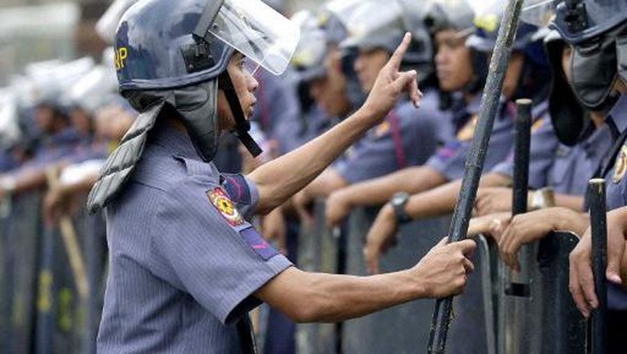 A police commander gives last minute instructions to a phalanx of riot police watching an anti-US protest near the presidential palace in Manila 22 January 2002. The protesters are denouncing the deployment of US troops in joint training against Muslim rebels in the southern Philippines, where the gunmen are holding an American couple hostage.  AFP PHOTO/Jay DIRECTO (Photo by JAY DIRECTO / AFP)