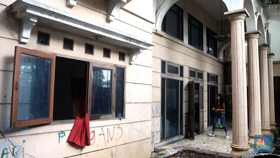 Petugas PPSU menebang pohon di depan rumah mewah terbengkalai yang viral di media sosial di Kawasan Jatinegara, Cakung, Jakarta, Kamis, (5/1/2023). (CNBC Indonesia/ Muhammad Sabki)