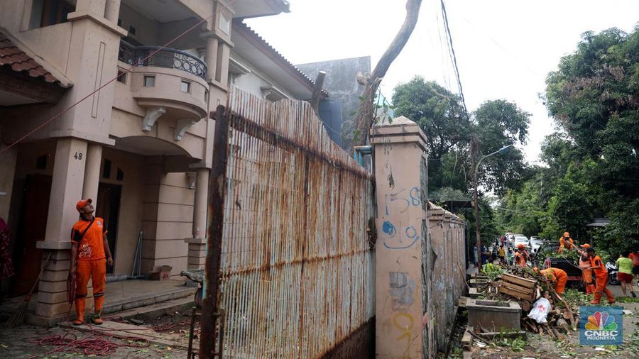 Petugas PPSU menebang pohon di depan rumah mewah terbengkalai yang viral di media sosial di Kawasan Jatinegara, Cakung, Jakarta, Kamis, (5/1/2023). (CNBC Indonesia/ Muhammad Sabki)
