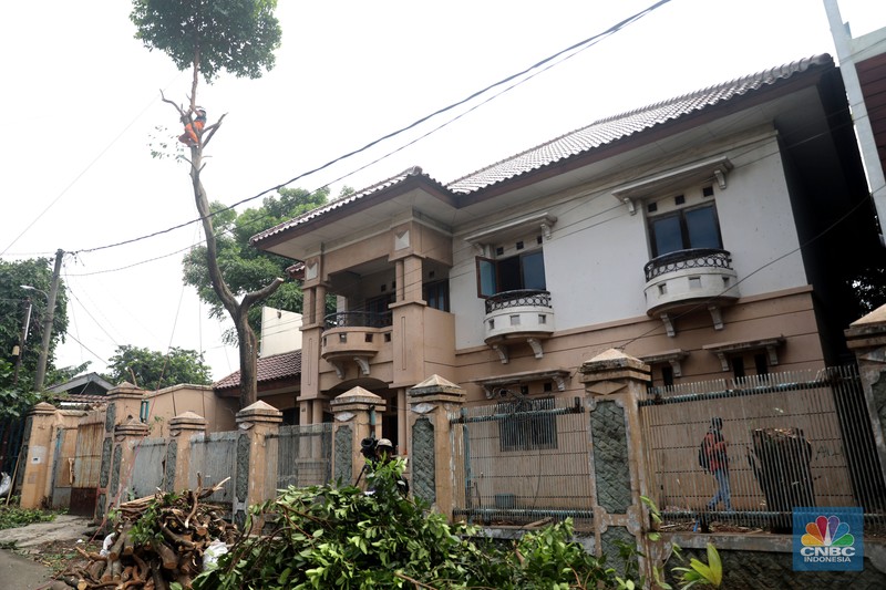 Petugas PPSU menebang pohon di depan rumah mewah terbengkalai yang viral di media sosial di Kawasan Jatinegara, Cakung, Jakarta, Kamis, (5/1/2023). (CNBC Indonesia/ Muhammad Sabki)