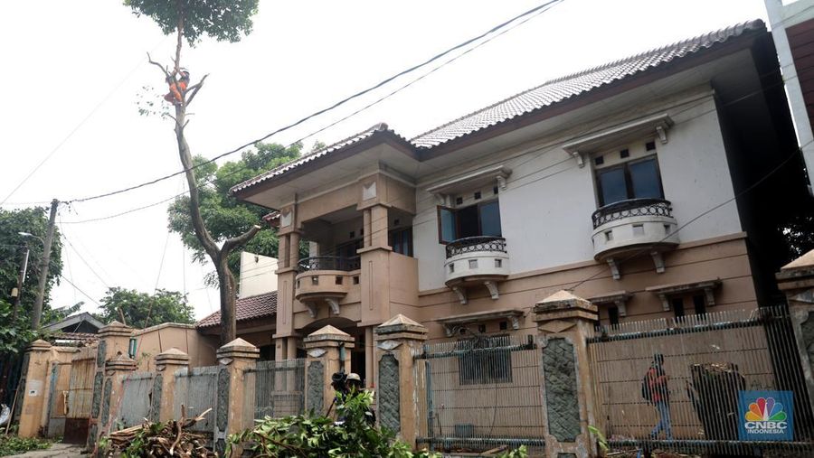 Petugas PPSU menebang pohon di depan rumah mewah terbengkalai yang viral di media sosial di Kawasan Jatinegara, Cakung, Jakarta, Kamis, (5/1/2023). (CNBC Indonesia/ Muhammad Sabki)