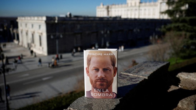 A woman poses for a photo as she opens a copy of 