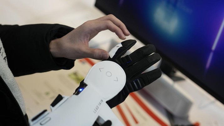 An attendee looks at Haptic Metaverse Gloves by AI Silk during the CES tech show Thursday, Jan. 5, 2023, in Las Vegas. (AP Photo/John Locher)
