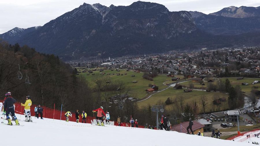 Athletes inspect the small strip of snow where they will compete in an alpine ski, men's World Cup slalom race, in Garmisch Partenkirchen, Germany, Wednesday, Jan. 4, 2023. Much of the Alps just don't look right for this time of year. Sparse snowfall and unseasonably warm winter weather in Europe’s central mountains are allowing grass to blanket hillsides across the region, causing headaches for ski slope operators and aficionados of Alpine white. (AP Photo/Alessandro Trovati)