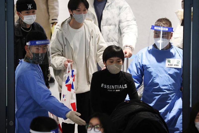 Petugas kesehatan memeriksa alat pelindung mereka di luar pusat pengujian COVID-19 di Bandara Internasional Incheon di Incheon, Korea Selatan, Kamis, 5 Januari 2023. (AP Photo/Lee Jin-man)