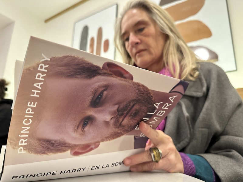 A woman poses for a photo as she opens a copy of 