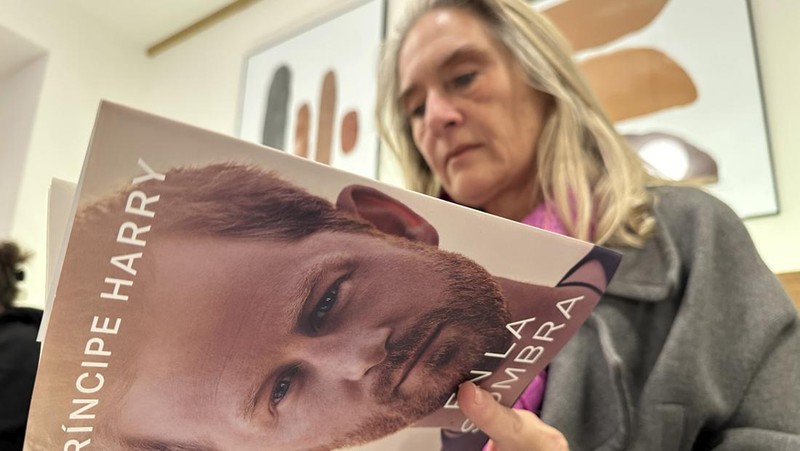 A woman poses for a photo as she opens a copy of 