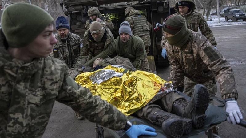 Ukrainian military medics carry a body of their killed comrade into a morgue in Donetsk region, Ukraine, Monday, Jan. 9, 2023. (AP Photo/Evgeniy Maloletka)
