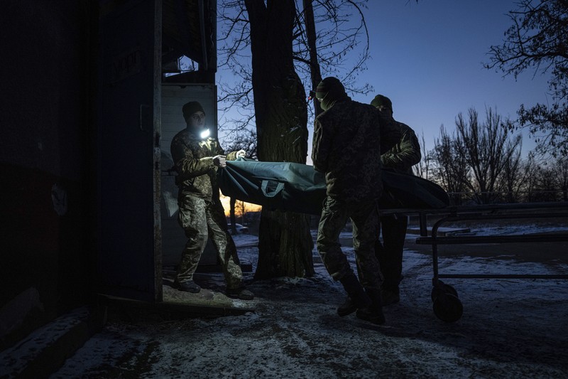 APTOPIX Russia Ukraine War Ukrainian military medics carry a body of their killed comrade into a morgue in Donetsk region, Ukraine, Monday, Jan. 9, 2023. (AP Photo/Evgeniy Maloletka)