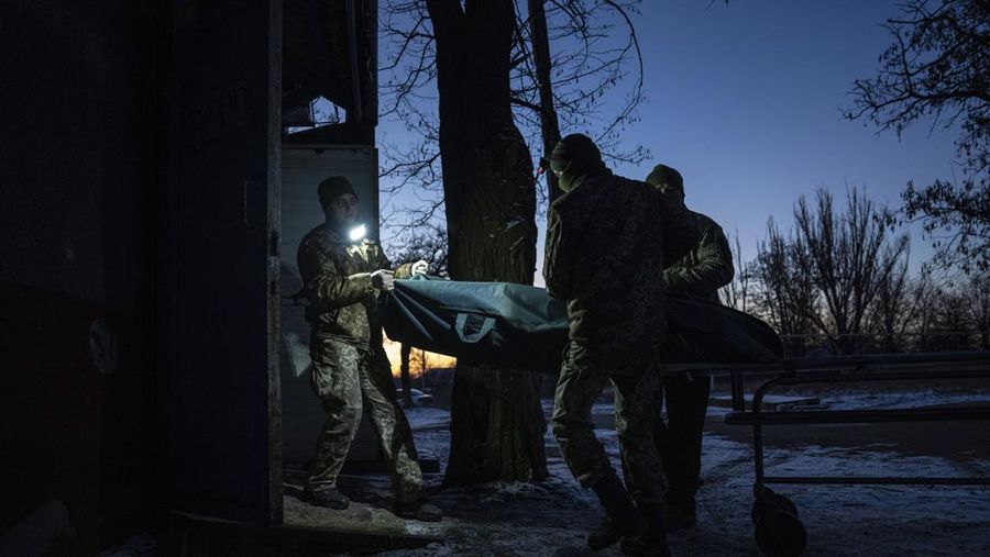 Ukrainian military medics carry a body of their killed comrade into a morgue in Donetsk region, Ukraine, Monday, Jan. 9, 2023. (AP Photo/Evgeniy Maloletka)