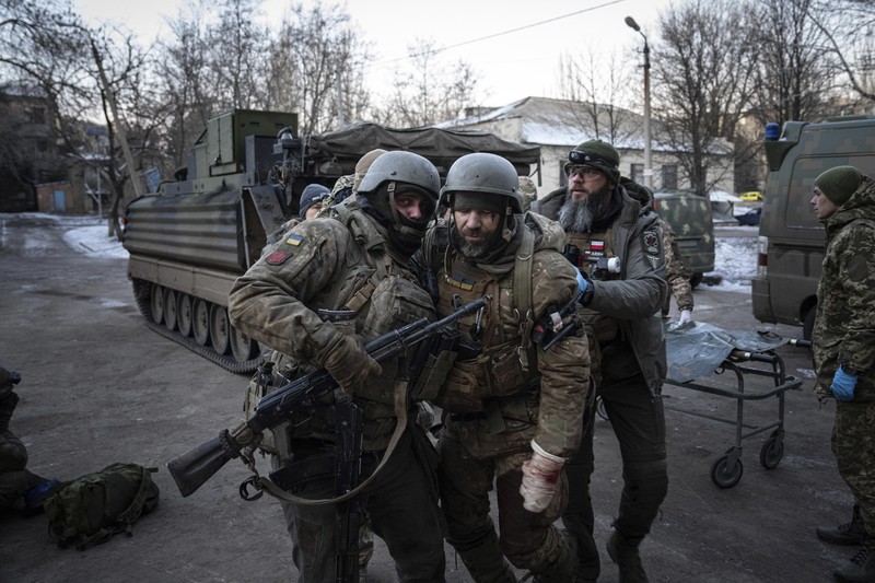 Ukrainian military medics carry a body of their killed comrade into a morgue in Donetsk region, Ukraine, Monday, Jan. 9, 2023. (AP Photo/Evgeniy Maloletka)
