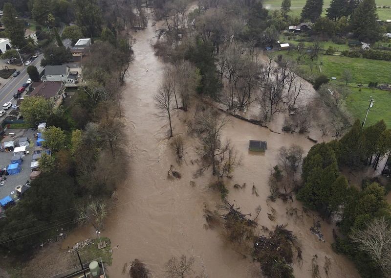 Uvas Creek membanjiri bagian Miller Avenue di Gilroy, California, saat rangkaian terbaru sungai di atmosfer menghantam Bay Area pada Senin, 9 Januari 2023. Uvas Creek membanjiri bagian Miller Avenue di Gilroy, California, saat rangkaian terbaru sungai di atmosfer menghantam Bay Area pada Senin, 9 Januari 2023. (Dai Sugano/Bay Area News Group via AP)