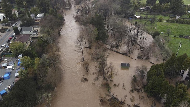 Uvas Creek membanjiri bagian Miller Avenue di Gilroy, California, saat rangkaian terbaru sungai di atmosfer menghantam Bay Area pada Senin, 9 Januari 2023. (Dai Sugano/Bay Area News Group via AP)
