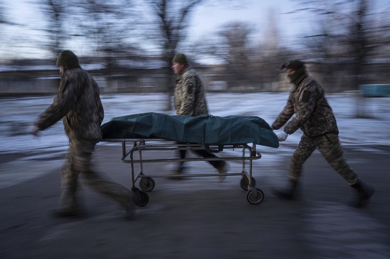 APTOPIX Russia Ukraine War Ukrainian military medics carry a body of their killed comrade into a morgue in Donetsk region, Ukraine, Monday, Jan. 9, 2023. (AP Photo/Evgeniy Maloletka)