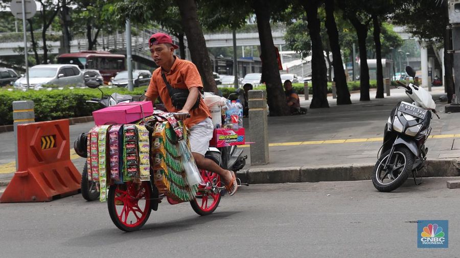 Pedagang kopi keliling menyiapkan minuman di kawasan Pedestrian Sudirman, Jakarta, Rabu, 11/1/2023. Pedagang kopi keliling atau kerap disebut starling sering terluhat hilir mudik setiap hari di jalan-jalan trotoar Jakarta. (CNBC Indonesia/ Muhammad Sabki)