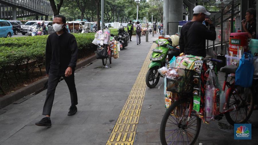 Pedagang kopi keliling menyiapkan minuman di kawasan Pedestrian Sudirman, Jakarta, Rabu, 11/1/2023. Pedagang kopi keliling atau kerap disebut starling sering terluhat hilir mudik setiap hari di jalan-jalan trotoar Jakarta. (CNBC Indonesia/ Muhammad Sabki)