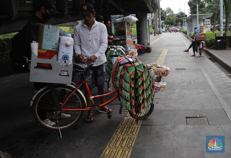 Pedagang kopi keliling menyiapkan minuman di kawasan Pedestrian Sudirman, Jakarta, Rabu, 11/1/2023. Pedagang kopi keliling menyiapkan minuman di kawasan Pedestrian Sudirman, Jakarta, Rabu, 11/1/2023. Pedagang kopi keliling atau kerap disebut starling sering terluhat hilir mudik setiap hari di jalan-jalan trotoar Jakarta. (CNBC Indonesia/ Muhammad Sabki)