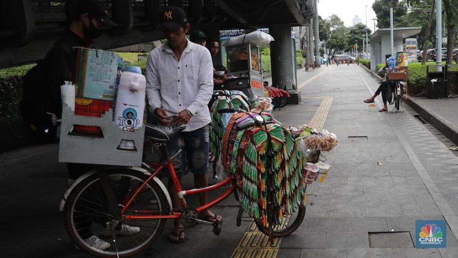 Pedagang kopi keliling menyiapkan minuman di kawasan Pedestrian Sudirman, Jakarta, Rabu, 11/1/2023. Pedagang kopi keliling atau kerap disebut starling sering terluhat hilir mudik setiap hari di jalan-jalan trotoar Jakarta. (CNBC Indonesia/ Muhammad Sabki)