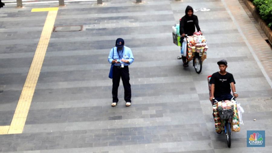 Pedagang kopi keliling menyiapkan minuman di kawasan Pedestrian Sudirman, Jakarta, Rabu, 11/1/2023. Pedagang kopi keliling atau kerap disebut starling sering terluhat hilir mudik setiap hari di jalan-jalan trotoar Jakarta. (CNBC Indonesia/ Muhammad Sabki)