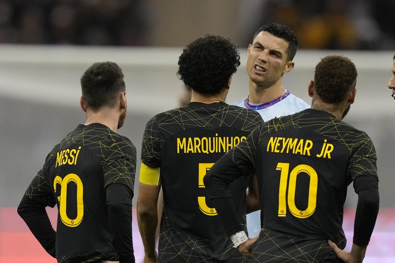 Cristiano Ronaldo meringis bermain untuk XI gabungan tim Arab Saudi Al Nassr dan Al Hilal diapit oleh pemain PSG Lionel Messi dan rekan setimnya Neymar dan Marquinhos selama pertandingan sepak bola persahabatan, di Stadion Universitas King Saud, di Riyadh, Arab Saudi, Kamis, 19 Januari 2023. Cristiano Ronaldo meringis bermain untuk XI gabungan tim Arab Saudi Al Nassr dan Al Hilal diapit oleh pemain PSG Lionel Messi dan rekan setimnya Neymar dan Marquinhos selama pertandingan sepak bola persahabatan, di Stadion Universitas King Saud, di Riyadh, Arab Saudi, Kamis, 19 Januari 2023. (AP Photo/Hussein Malla)