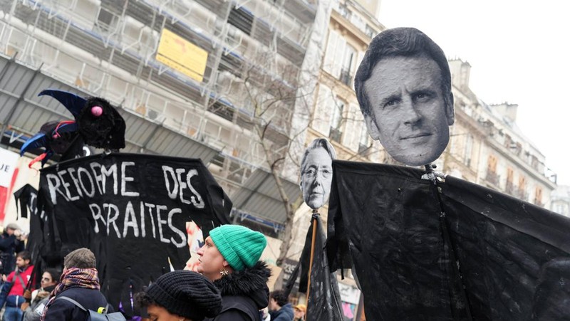 Para pengunjuk rasa berbaris melalui jalan-jalan Paris sebagai bagian dari protes dan pemogokan nasional terhadap rencana reformasi Pensiun Presiden Macron dan kenaikan biaya hidup pada 19 Januari 2023 di Paris, Prancis. Menyusul pengumuman pemerintah Prancis untuk mendorong usia pensiun dari 62 menjadi 64, serikat pekerja menyerukan aksi sosial massal dengan karyawan di bidang transportasi, pendidikan, energi, dan layanan kesehatan bergabung dengan pemogokan nasional, dengan protes besar di seluruh Prancis. Serikat CGT Prancis juga mengancam akan memutus pasokan listrik untuk anggota parlemen dan pengusaha di tengah pemogokan nasional. (Kiran Ridley/Getty Images)