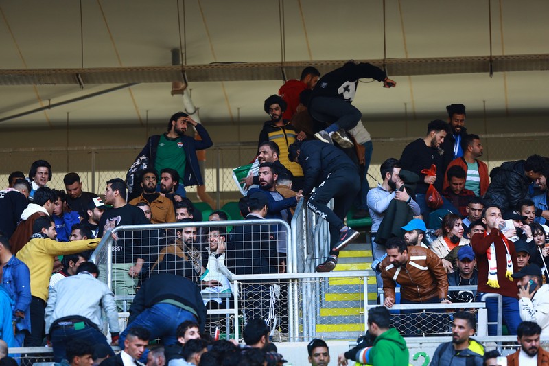 Anggota tim keamanan stadion Irak membawa seorang penggemar sepak bola yang terluka ke area darurat di Stadion Internasional Basra menyusul penyerbuan menjelang pertandingan final Piala Teluk Arab malam ini antara Irak dan Oman, pada 19 Januari 2023 di Basra. - Satu orang tewas dan puluhan lainnya terluka ketika terjadi penyerbuan di luar stadion sepak bola di Irak selatan beberapa jam sebelum final Piala Teluk, kata sumber medis dan keamanan. (HUSSEIN FALEH/AFP via Getty Images)